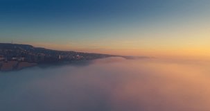 Flying above sky clouds and aerial view toward city and beach shore. Sunset over Varna, Bulgaria cityscape, 4k video