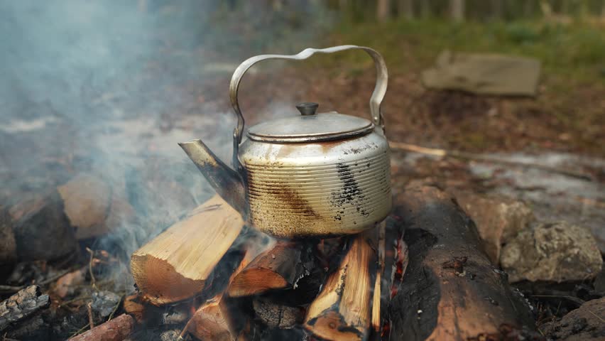 Coffee in a kettle on campfire in forest. Travel and camping concept.