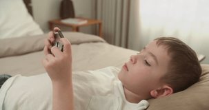 Cute child girl School Boy holds a phone, kid using smartphone, child browsing the Internet, talking on smart phone, uses video communication at home on the phone. 4K
