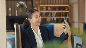 Close-up Youth Asia female passenger with suit wear earphone sit couch video call phone show luxury life social media in modern airline lounge wait for transit at airport. Hotel travel trip concept.