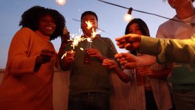 Group of multiracial friends enjoying a rooftop party with sparklers. Young people enjoying new year's eve. - Powered by Shutterstock - Get 15% off with code: PIKWIZARD15