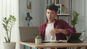 Asian man suffering from lower back pain while working at home
