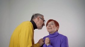 Happy elderly couple in love. Old man whispering secret to his wife. Gray-haired man and woman are standing isolated. Woman laughs cheerfully. 4k video footage - Powered by Shutterstock - Get 15% off with code: PIKWIZARD15