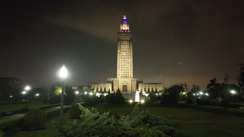 Louisiana state capitol building in Baton Rouge, Louisiana at night with drone video moving up.