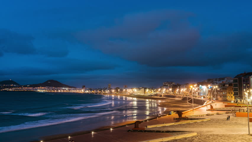Timelapse of the island of las palmas de gran canarias, spain, view of the beach la cícer and playa de las canteras with movement of clouds and tourists walking along the waterfront, from day to night