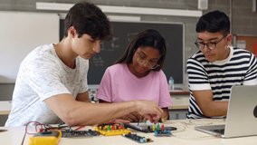 Group of diverse teenage high school students learning together to build electronic circuits at classroom. Millennial ethnic classmates working at technology class - Powered by Shutterstock - Get 15% off with code: PIKWIZARD15
