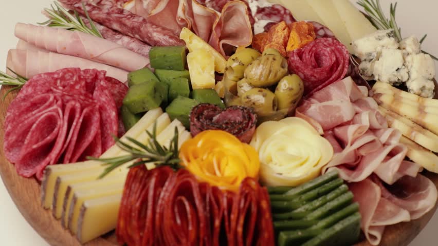 Charcuterie and cheese platter rotates smoothly around its axis. Appetizers boards with assorted cheese, salami, ham, grape and nuts. Top view. Video is looped