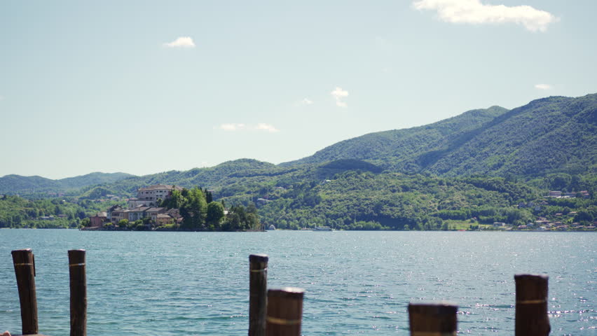 A beautiful woman reads a book by Lake Orta in Italy. Warm summer sun and vacation. Surrounded by the natural beauty of the Italian countryside and hills.