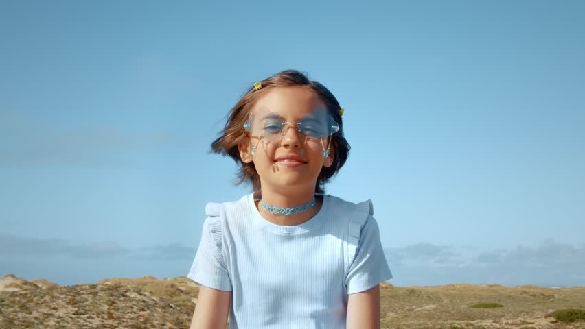 Caucasian girl wearing sunglasses smiling toothy to the camera while spending time at the open air