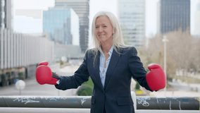 Mature aggressive businesswoman screaming clashing boxing gloves outdoors - Powered by Shutterstock - Get 15% off with code: PIKWIZARD15