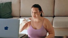 Joyful full figured woman wiping face and looking at laptop while preparing for video call