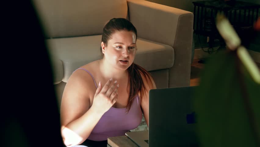 Joyful full figured woman talking to laptop while videocalling with friend at home Royalty-Free Stock Footage #1102484829