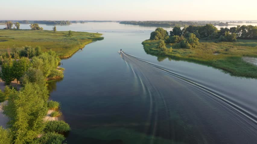 Aerial morning view to Dnieper river with motor boat and trail on calm water near Cherkasy, Ukraine | Shutterstock HD Video #1102485689