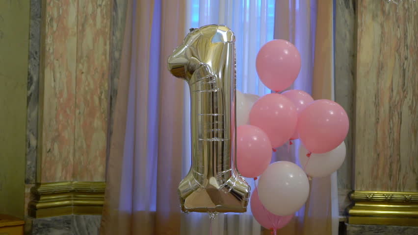 Balloons at the party decorated. White and pink round ballon. Silver 1 year party birthday celebration. Bday party indoors, one year old. Childhood.