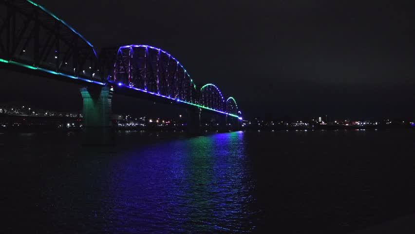The Big Four Pedestrian Bridge in Louisville Kentucky Crossing the Ohio River at Night with Light Display 4k. Colorful Light Shows, Indiana Shore, City Lights.