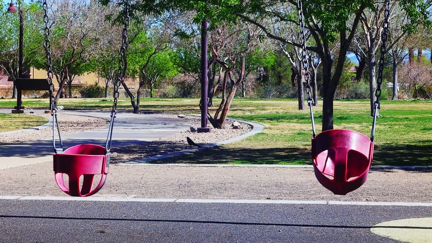 Empty swings in metro park on sunny afternoon, 