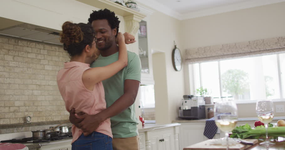 Happy biracial couple hugging in kitchen while cooking. love and relationship, enjoying quality leisure time at home. | Shutterstock HD Video #1102491677