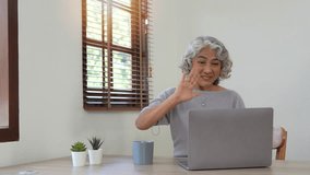 Cheerful elderly lady staying in touch with her friends or family via video connection, video call