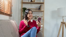 Young asian woman Making video call with family or friends on sofa in living room
