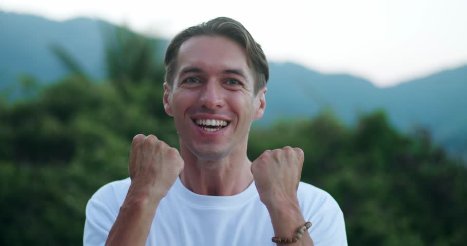 Man shows WOW emotion. Portrait of shocked male winner delighted celebrating lucky win. Excited man rejoices in victory, standing against the backdrop of scenic nature outdoors. Winning concept