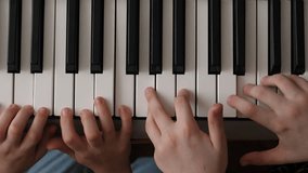 two pairs of children's hands playing the piano, top view. children spend their leisure time playing a musical instrument. learning to play the piano synthesizer, family hobbies - Powered by Shutterstock - Get 15% off with code: PIKWIZARD15