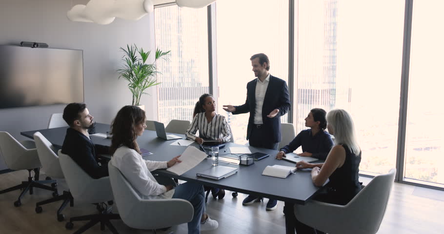 Millennial businessman in suit makes speech standing in front of company clients, investors or partners, take part in formal meeting, corporate training for staff members, commercial deal discussion Royalty-Free Stock Footage #1102501789