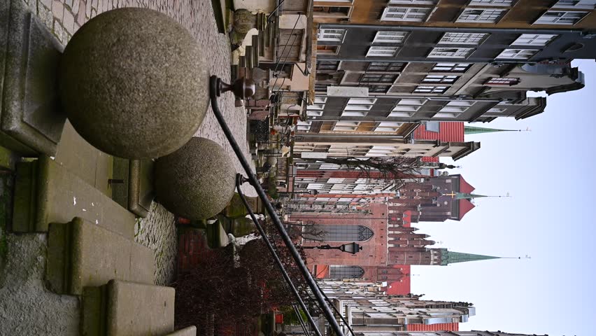 VERTCAL VIDEO, Narrow historic street of the Old Town, Co-Cathedral Basilica of the Assumption of the Blessed Virgin Mary, kamienne kule, metalowa zabytkowa balustrada