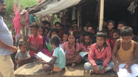 Noida, Uttar Pradesh,India - September 2019: Education system, Students from rural or slum areas getting educated by teacher at school of Indian village area in open space.  : vidéo de stock éditoriale