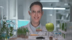 Skilled woman geneticist examining green apple and injects pesticides into it with a syringe. Biological experiment with fruits in the laboratory, educational science experiments. GMO. Close up. - Powered by Shutterstock - Get 15% off with code: PIKWIZARD15