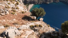 Drone video capturing the pristine Butterfly Valley in Ölüdeniz, Fethiye, featuring its tranquil beach, canyon, waterfall, and boats cruising along the vibrant turquoise sea.