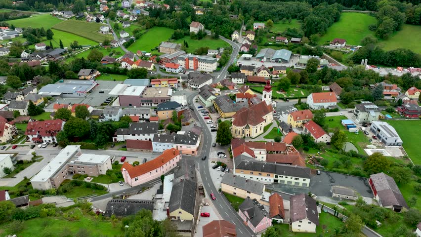 ALPS, AUSTRIA - OCTOBER, 2022: Aerial view of austrian mountain village Lendorf and beautiful valley. Green meadows and autumn forest with yellow leaves around.