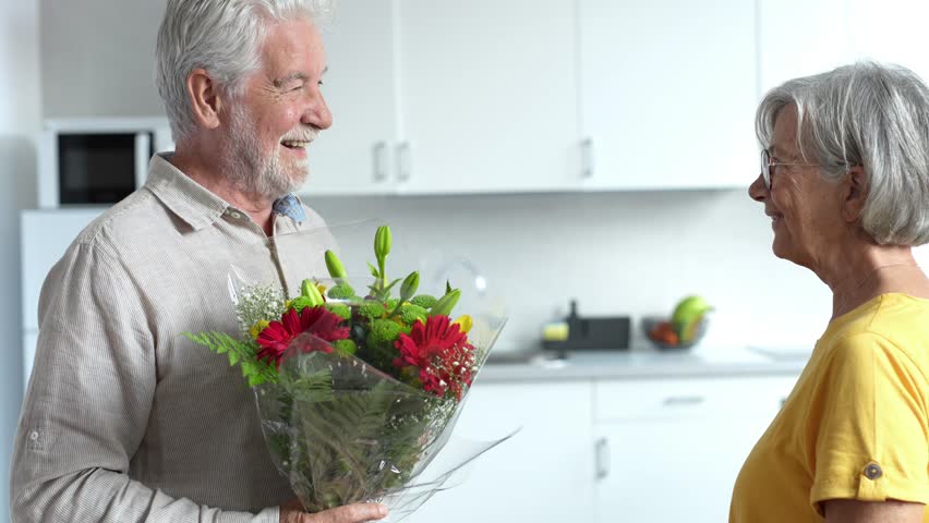 Old man giving flowers at his wife sitting on the sofa at home for the San Valentines’ day. Pensioners enjoying surprise together. In love people having fun.
 Royalty-Free Stock Footage #1102513597