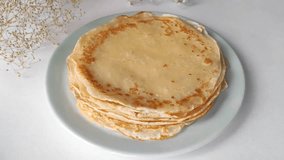 Thin pancakes on a plate. Women's hands roll a pancake into a tube.
Hot pancakes for breakfast