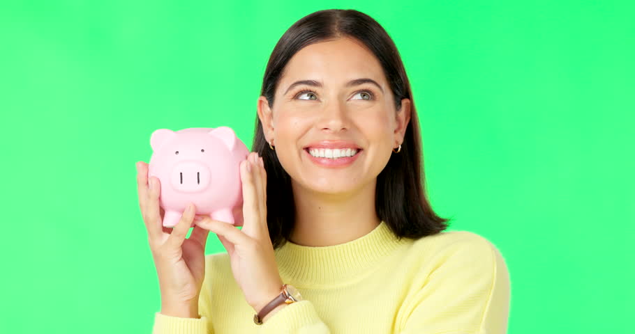 Happy woman, face and money with piggy bank on green screen for investment, budget or finance against a studio background. Portrait of excited female holding savings for coin, profit or investing