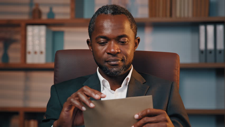 Successful african american businessman in office open paper envelope read letter good news received bank loan approval profitable proposition happy man get promotion career advance great opportunity Royalty-Free Stock Footage #1102527725