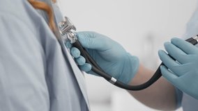 A female doctor listens to a patient with a stethoscope. A young woman at a medical examination. Diagnosis in a health care clinic. Hospital admission, treatment of heart and lung diseases. - Powered by Shutterstock - Get 15% off with code: PIKWIZARD15