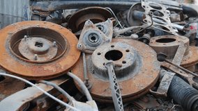 Rusty old wrecked car details. old metal car repair parts on ground. Many Used Rusty parts: clutch, spark plugs. Deteriorated Rust Car Engine Parts in junk yard pan under natural lighting. 4 k video