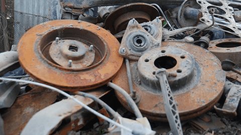 Rusty old wrecked car details. old metal car repair parts on ground. Many Used Rusty parts: clutch, spark plugs. Deteriorated Rust Car Engine Parts in junk yard pan under natural lighting. 4 k videoの動画素材