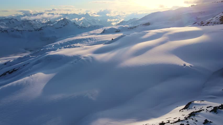 Aerial view of the two-headed peak of Mount Elbrus at sunset. Downhill skiing on the south-eastern slope. Chairlift to Garabashi station and the power line. Caucasus mountains Royalty-Free Stock Footage #1102534557