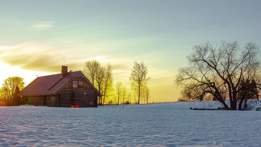 Sunrise to sunset time lapse of a cozy cabin in the winter landscape