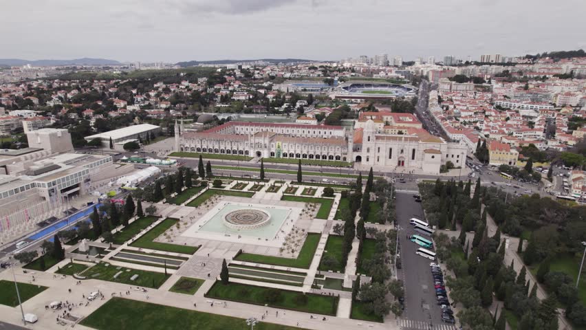 Aerial view orbiting Jerónimos Monastery ornate symmetrical gardens fountain behind Portuguese religious historical building