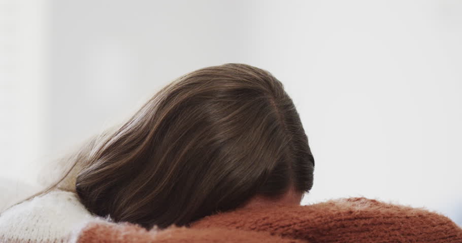 Sad caucasian teenage girl sitting on bed and covering her face. Mental health, emotion and lifestyle.