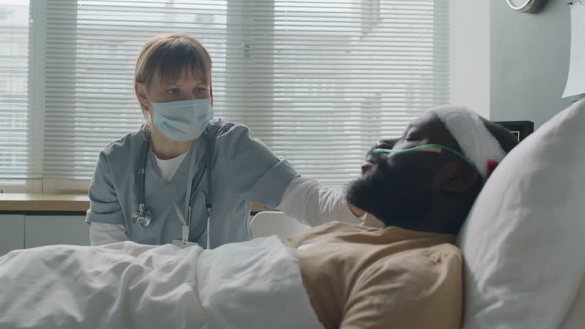 Practitioner wearing mask sitting in front of African American soldier with head injury comforting him and giving recommendations