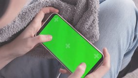 Teenager girl playing game on phone with green screen. Phone with greenscreen and chroma key for copy space. Chromakey mock up with tracking markers. Tap to click on centre of screen