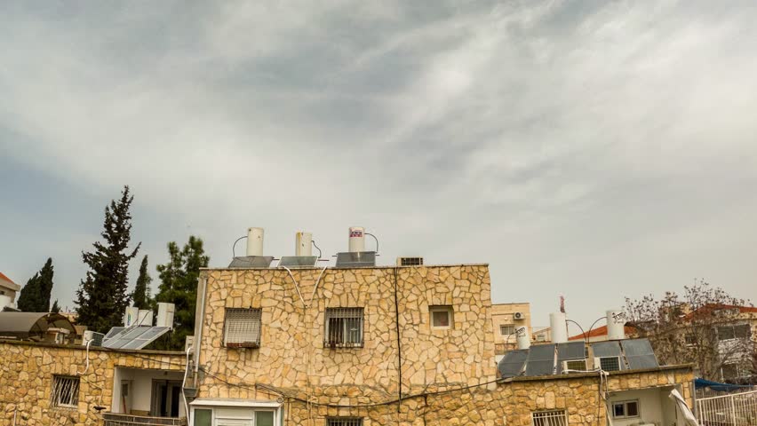 Timelapse shot of clouds passing over a residential building in Jerusalem, a blue spring sky full of clouds