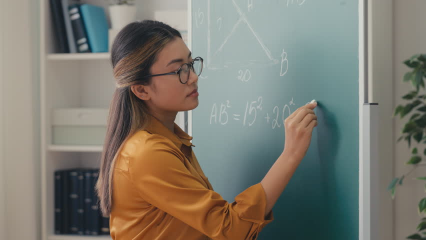 Asian woman teacher writing geometry equation on chalkboard, talking to students Royalty-Free Stock Footage #1102546153