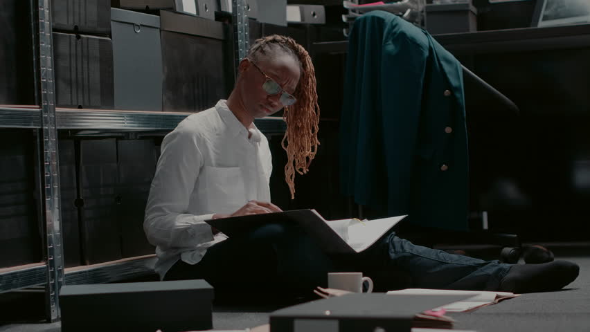 Female detective reading records on criminal case, trying to solve felony with evidence and surveillance photos. Law agent examining security information and checking suspect research. Handheld shot.