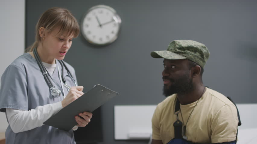 African American soldier signing paper to get discharged from military hospital and doing handshake with doctor