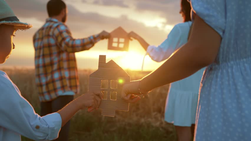 Family dream home, holding symbols of home, cardboard figures of house, love and happiness of parents and children, walking on picturesque golden field with wheat,bright sunshine in sunset. | Shutterstock HD Video #1102555611