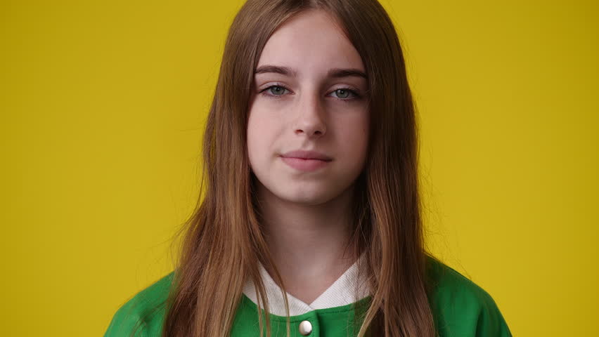 4k video of one girl who posing with a negative facial expression over yellow background.